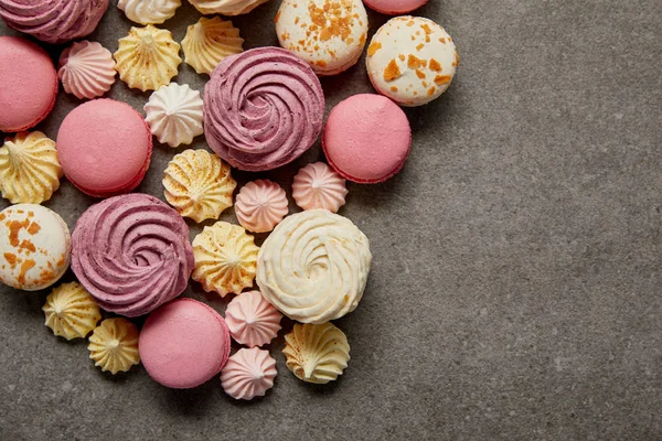 Vista dall'alto di deliziosi macaron francesi assortiti con meringhe su sfondo grigio — Foto stock