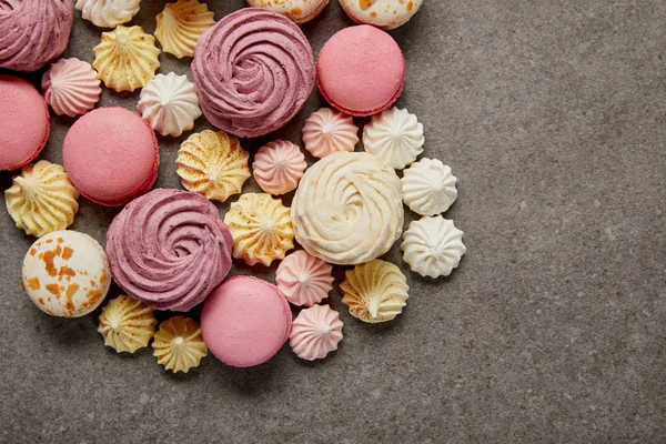 Top view of meringues, macaroons and fluffy white and pink zephyr on gray background — Stock Photo