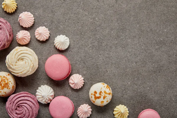 Top view of small meringues, pink and white macaroons and pink soft zephyr on gray background — Stock Photo