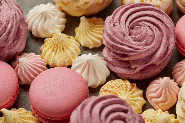 Zéfiro rosa com pequenos merengues amarelos e rosa e macaroons rosa no fundo cinza — Fotografia de Stock