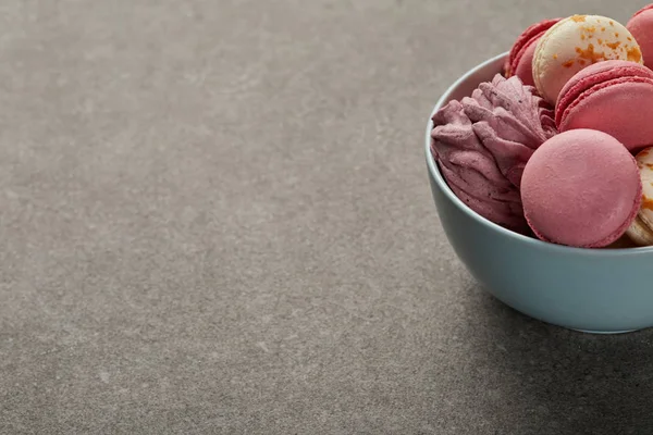 Deliciosos macaroons rosa e branco com zephyr em tigela azul sobre fundo cinza — Fotografia de Stock