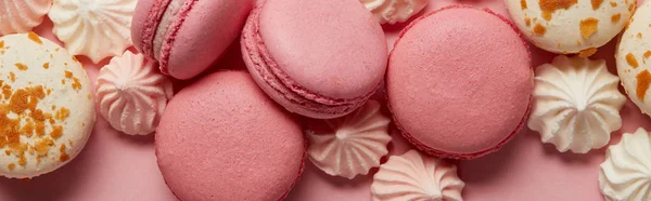 Deliciosos macarrones surtidos con pequeños merengues rosados y blancos sobre fondo rosado - foto de stock