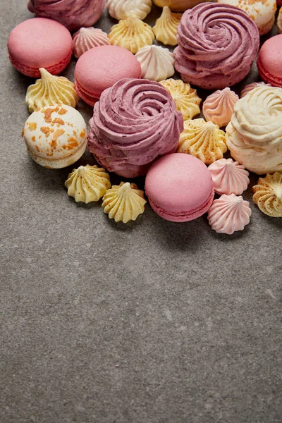 Tasty assorted small meringues, soft zephyr with french macaroons on gray background — Stock Photo