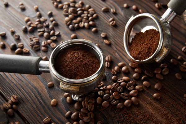 Portafiltri con caffè fresco aromatico su superficie di legno scuro con chicchi di caffè — Foto stock