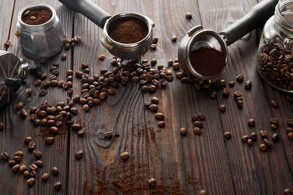 Geyser coffee maker near portafilters and glass jar on dark wooden surface with coffee beans — Stock Photo