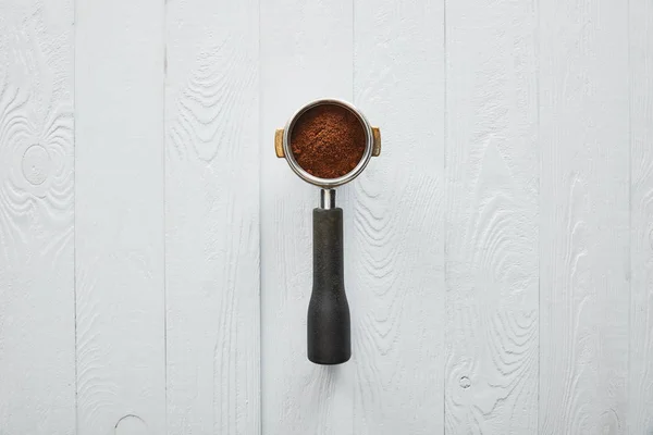 Top view of portafilter with coffee on white wooden surface — Stock Photo