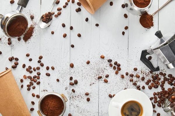 Vista superior de portafilters, colheres, copos de papel, cafeteira geyser e xícara de café na superfície de madeira branca — Fotografia de Stock