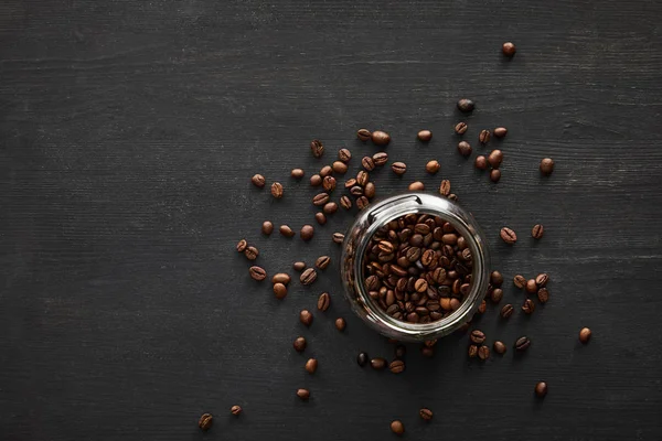 Vista superior del frasco de vidrio lleno de granos de café en la superficie oscura - foto de stock