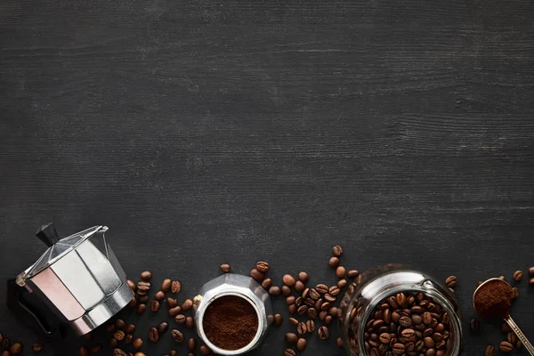 Vista superior de las partes de la cafetera géiser cerca del frasco de vidrio y cuchara en la superficie de madera oscura con granos de café - foto de stock