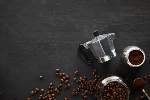 Vista superior de las partes de la cafetera géiser cerca de cuchara y frasco de vidrio en la superficie de madera oscura con granos de café - foto de stock