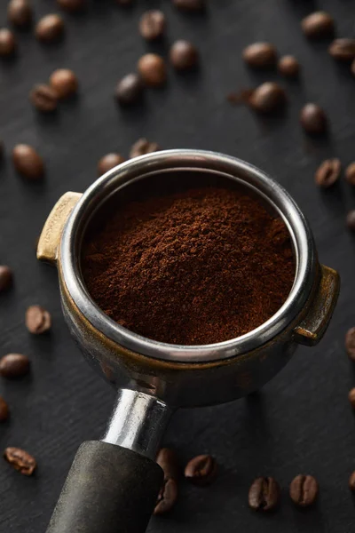 Portafilter with fresh ground coffee on dark wooden surface with coffee beans — Stock Photo
