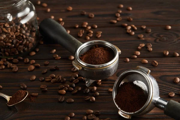 Portafilters near geyser glass jar with coffee and spoon on dark wooden surface — Stock Photo