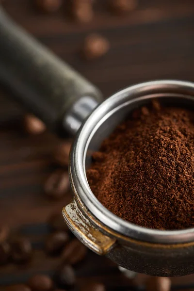 Portafilter preenchido com café moído fresco sob superfície escura com grãos de café — Fotografia de Stock