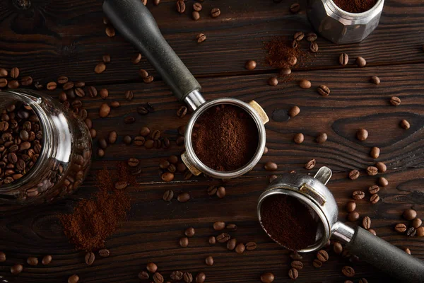 Portafilters entre frasco de vidro e máquina de café geyser na superfície de madeira escura — Fotografia de Stock