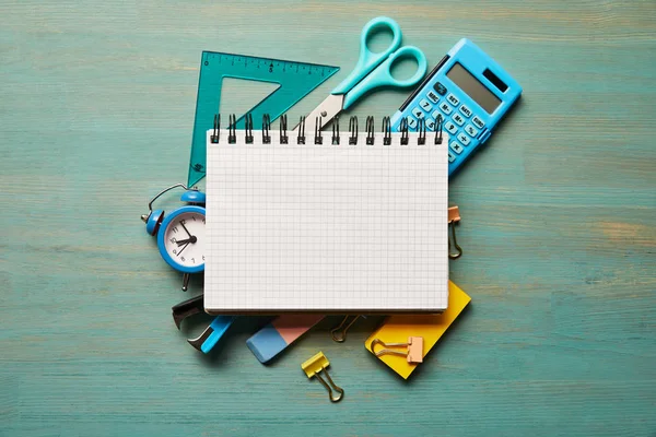 Vue du haut du carnet vierge près des fournitures scolaires bleues à la table en bois turquoise — Photo de stock