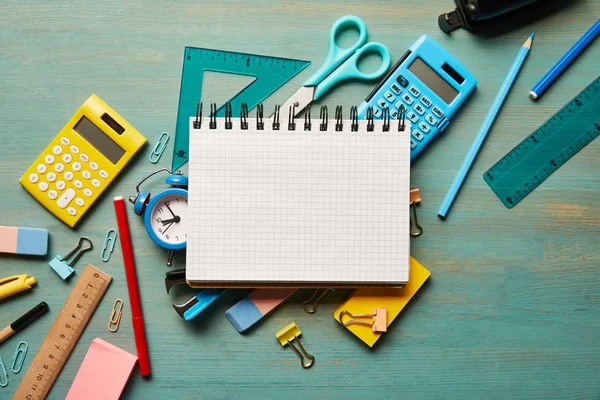 Vista dall'alto del taccuino vuoto vicino alle forniture scolastiche al tavolo di legno turchese — Foto stock