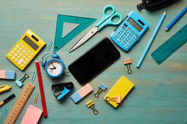 Vista superior do smartphone com tela em branco perto de material escolar na mesa de madeira turquesa — Fotografia de Stock