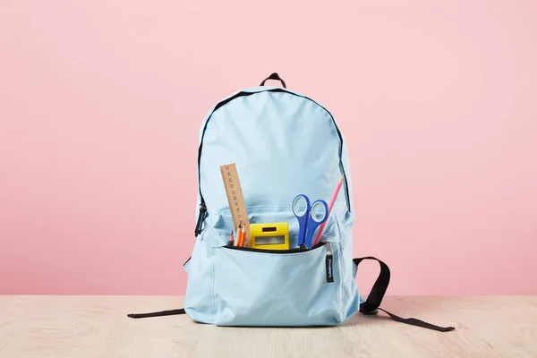 Zaino scuola blu con cancelleria in tasca isolato su rosa — Foto stock