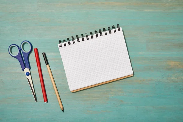 Vue du dessus du bloc-notes vide près du crayon, des ciseaux et du stylo feutre sur le bureau en bois — Photo de stock