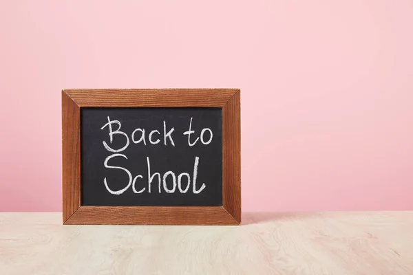 Lavagna con iscrizione di ritorno a scuola isolata su rosa — Foto stock