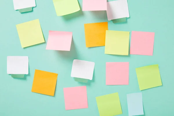 Multicolored empty sticky notes with copy space on turquoise wall — Stock Photo