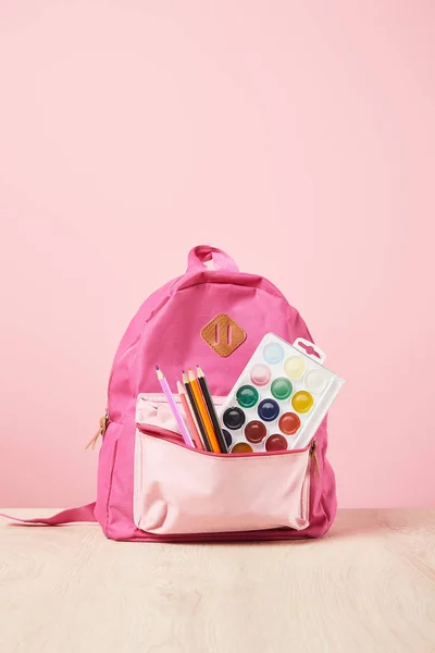 Pink backpack with supplies in pocket isolated on pink — Stock Photo