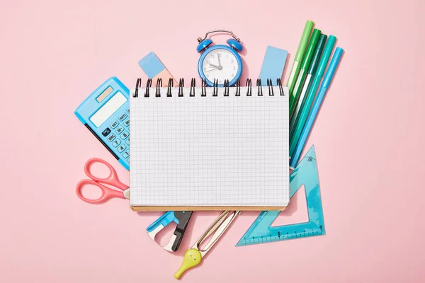 Top view of school supplies near blank notebook isolated on pink — Stock Photo