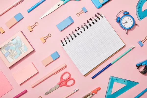Flache Liege mit blauem und rosa Schulmaterial und leerem Notizbuch isoliert auf rosa — Stockfoto