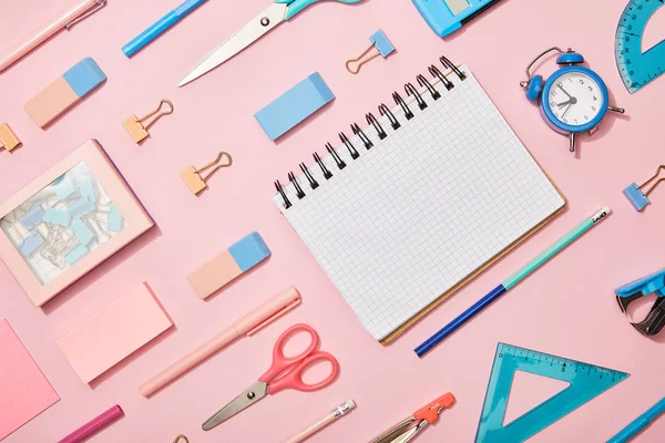 Couché plat avec des fournitures scolaires bleues et roses et carnet vierge isolé sur rose — Photo de stock