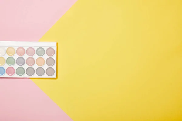 Top view of watercolor paints on pink and yellow background — Stock Photo