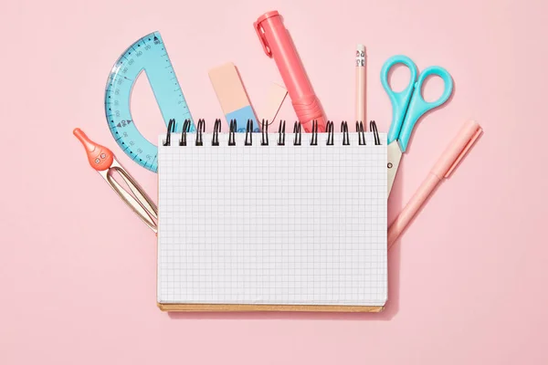Vista superior do caderno em branco entre os materiais escolares sobre fundo rosa — Fotografia de Stock