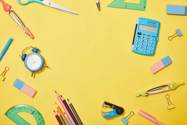 Top view of school supplies scattered on yellow background with copy space — Stock Photo