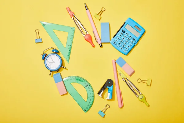 Top view of school supplies scattered on yellow background — Stock Photo