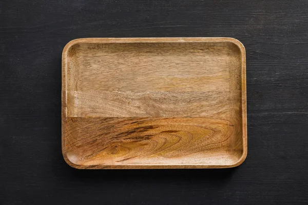 Vista superior do prato vazio de madeira marrom na superfície escura — Fotografia de Stock