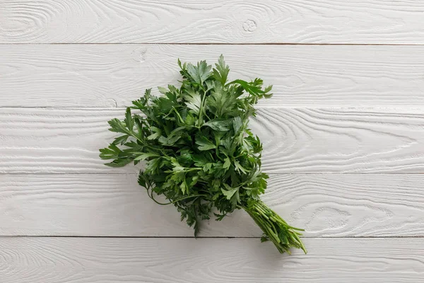 Vue de dessus du faisceau de persil vert frais sur une surface en bois blanc — Photo de stock