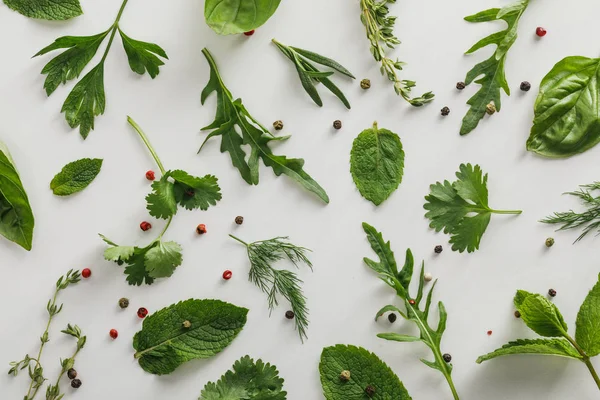 Top view of arugula, basil, cilantro, dill, parsley, rosemary and thyme twigs with peppercorns on white background — Stock Photo