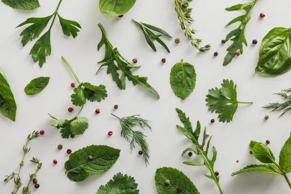 Vista dall'alto di rucola, basilico, coriandolo, aneto, prezzemolo, rosmarino e ramoscelli di timo con grani di pepe su sfondo bianco — Foto stock