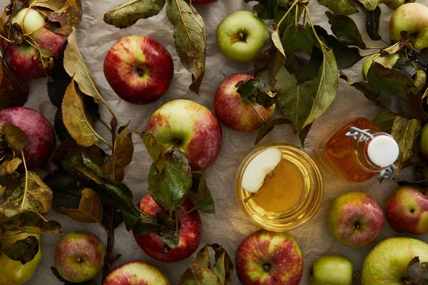 Vista superior de maçãs maduras com folhas perto de vidro e garrafa de cidra — Fotografia de Stock