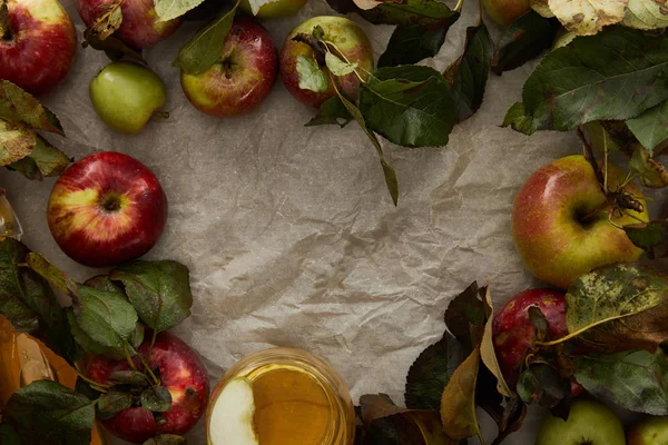 Vue de dessus des pommes avec feuilles et verre de cidre sur papier parchemin avec espace de copie — Photo de stock