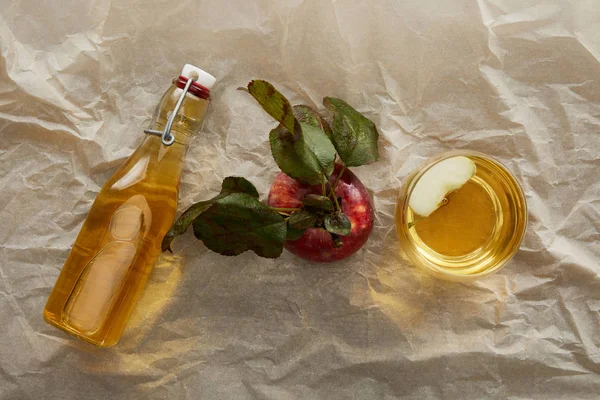 Top view of apple, bottle and glass of fresh cider on parchment paper with copy space — Stock Photo