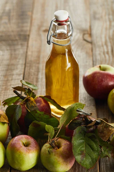 Flasche frischer Apfelwein in der Nähe von Äpfeln auf Holzoberfläche — Stockfoto