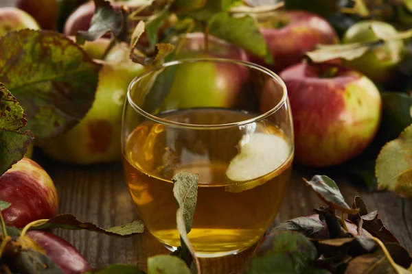 Glas frischer Apfelwein in der Nähe von Äpfeln auf Holzoberfläche — Stockfoto