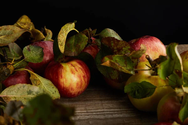 Manzanas frescas maduras y hojas en la superficie de madera aisladas en negro — Stock Photo