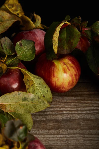 Fresh ripe red apples with leaves on wooden surface — Stock Photo