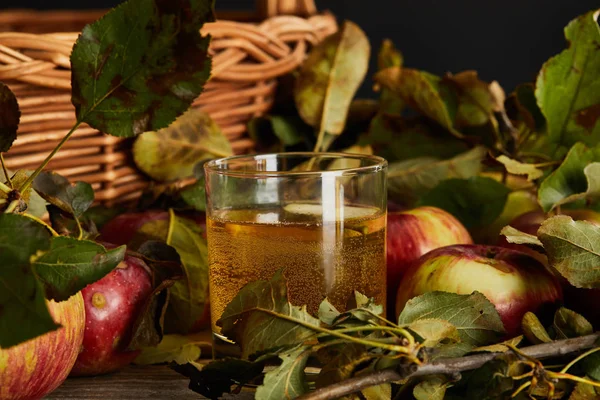 Glass of cider near wicker basket and apples — Stock Photo