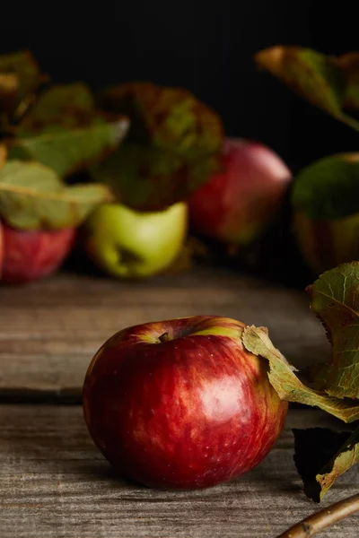 Red ripe apples with leaves on wooden surface isolated on black — Stock Photo