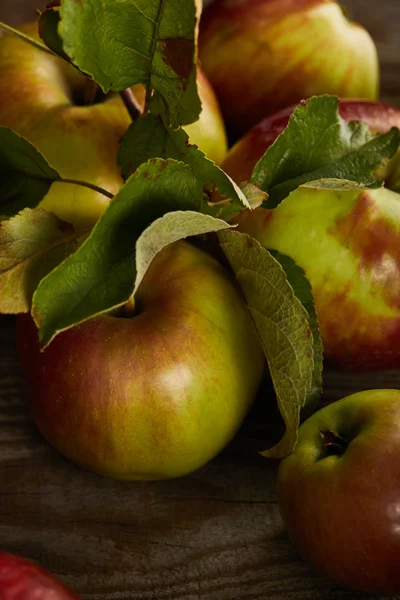 Vista de cerca de manzanas frescas jugosas con hojas en la superficie de madera - foto de stock