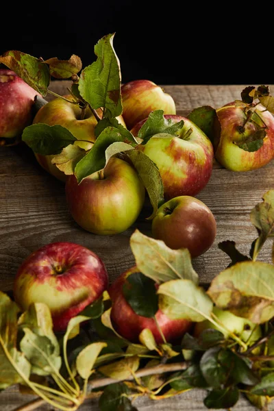 Fresh apples with leaves near branch on wooden surface isolated on black — Stock Photo