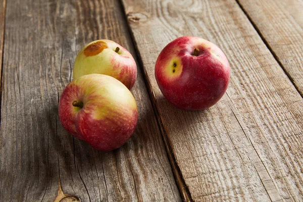 Agriculteurs pommes avec petite tache pourrie sur la surface en bois — Photo de stock