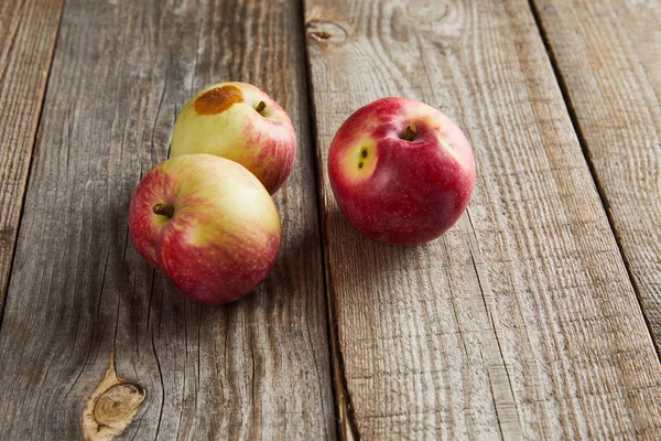 Farmers apples with small rotten spot on brown wooden surface — Stock Photo